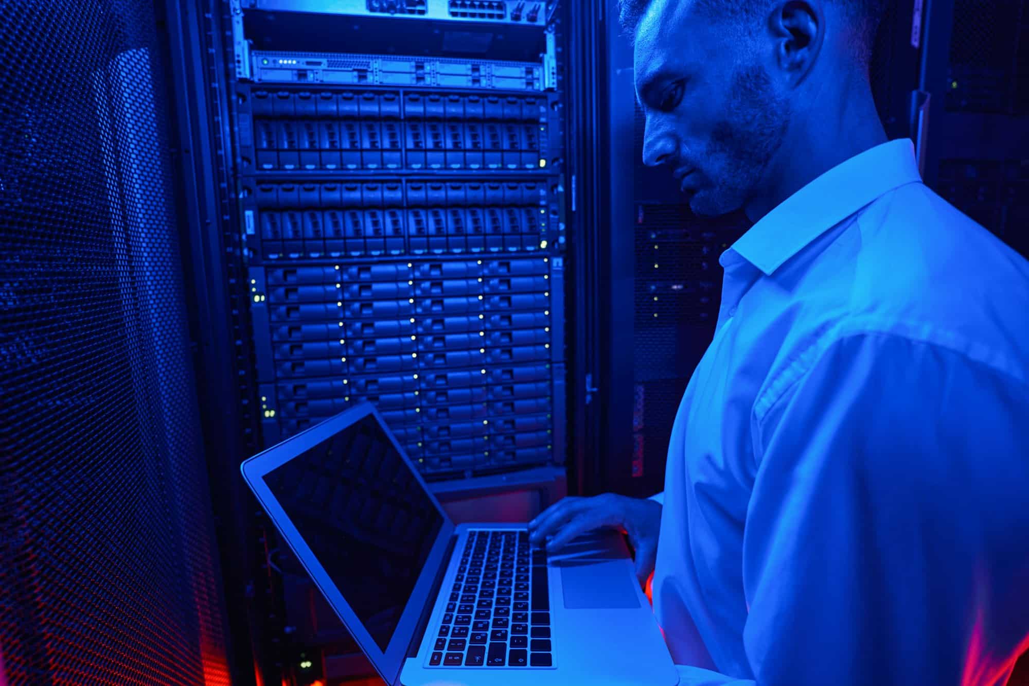 System administrator troubleshooting server rack with laptop